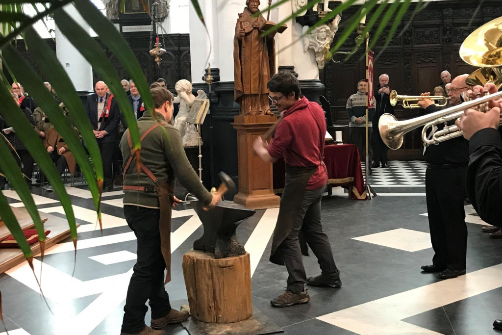 Bruno Kristo en Olivier Sarrazyn hameren op het aambeeld met het beeld van Sint-Elooi op de achtergrond 