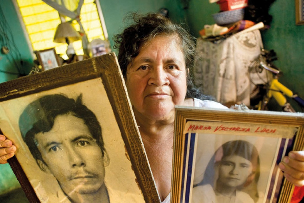 Een nabestaande uit Santa Lucia Cotzumalguapa toont portretten van familieleden die omkwamen bij de boerenprotesten in de jaren 1980.